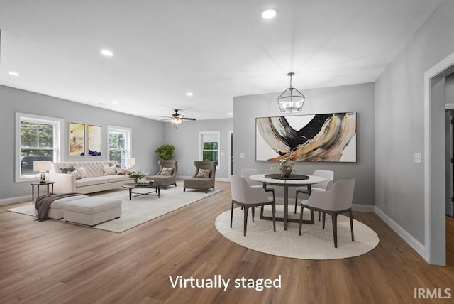 dining area featuring wood-type flooring and ceiling fan with notable chandelier