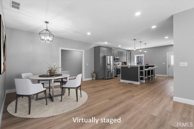 dining room with light hardwood / wood-style floors and a chandelier