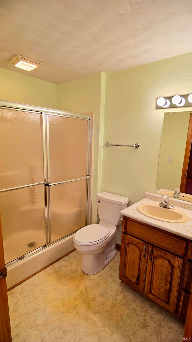 bathroom featuring toilet, a shower with door, and vanity