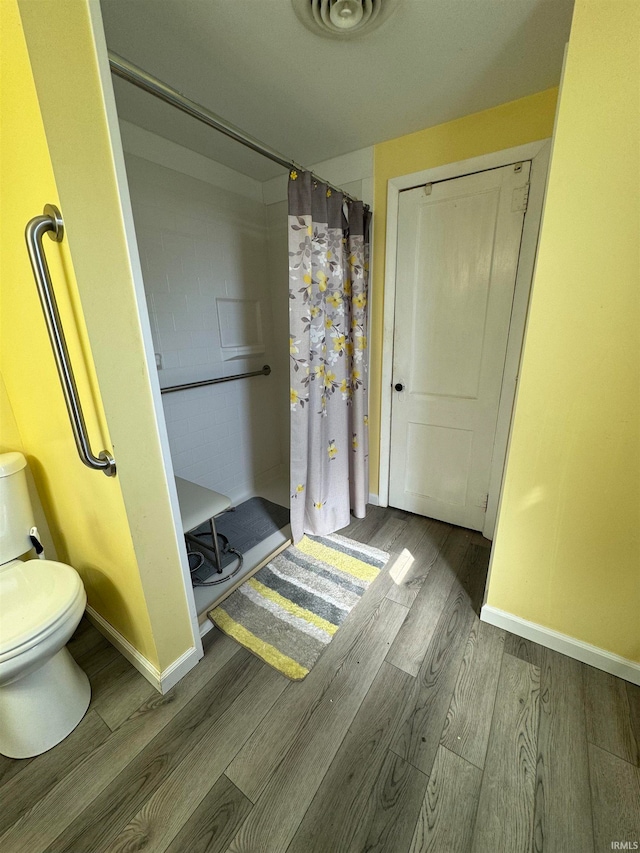 bathroom featuring toilet, curtained shower, and wood-type flooring