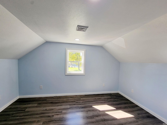 additional living space with lofted ceiling, dark hardwood / wood-style floors, and a textured ceiling