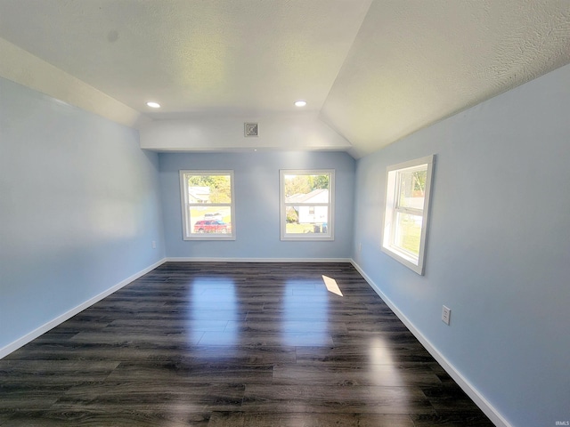 empty room featuring lofted ceiling, dark wood-type flooring, and a textured ceiling