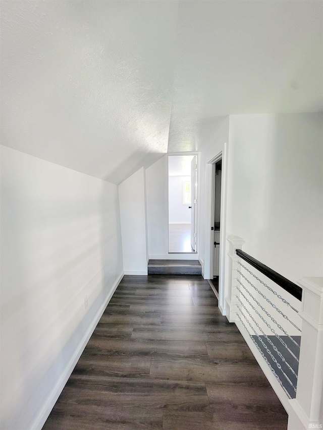 corridor featuring vaulted ceiling and dark hardwood / wood-style flooring