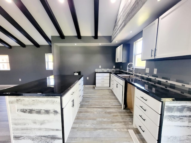 kitchen featuring beam ceiling, sink, light hardwood / wood-style flooring, backsplash, and white cabinetry