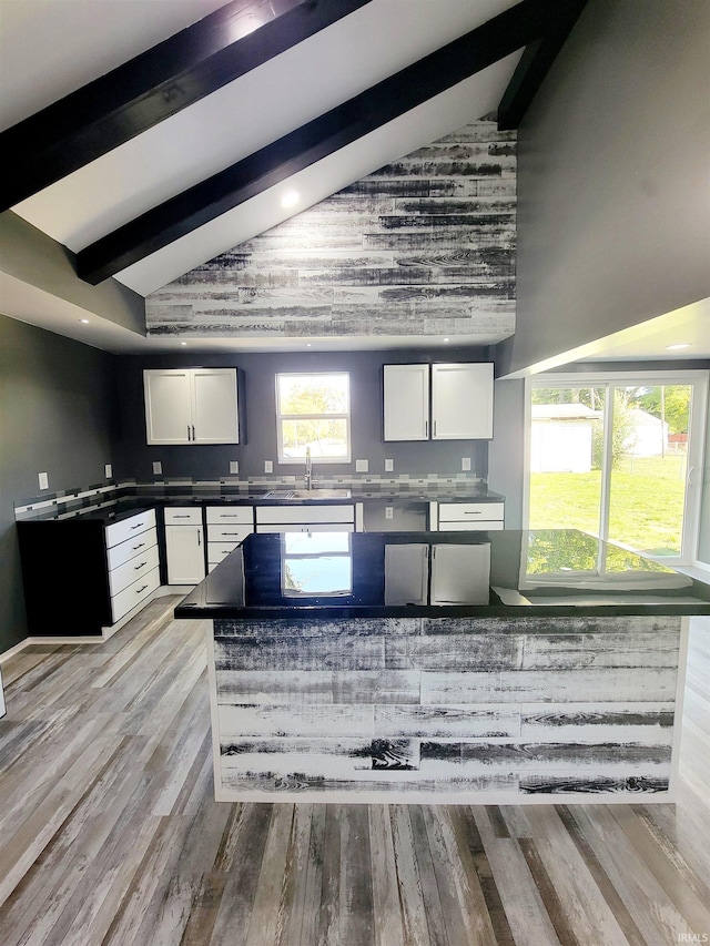 kitchen featuring white cabinets, light wood-type flooring, beam ceiling, and high vaulted ceiling