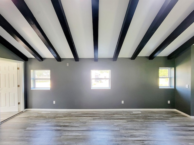 empty room with beamed ceiling, light hardwood / wood-style flooring, and plenty of natural light