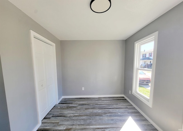 unfurnished bedroom featuring a closet, dark wood-type flooring, and multiple windows