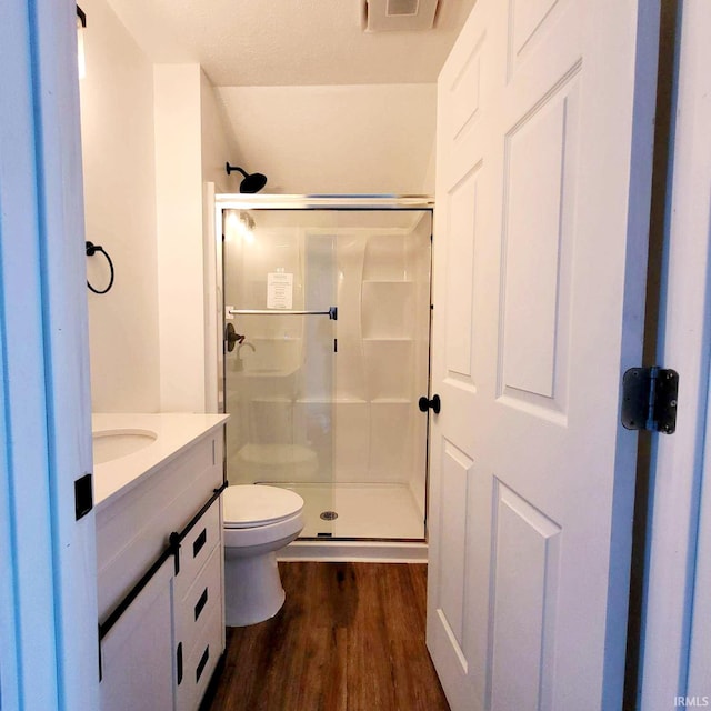 bathroom featuring vanity, wood-type flooring, a shower with shower door, toilet, and a textured ceiling