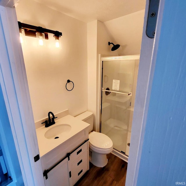 bathroom with wood-type flooring, vanity, toilet, and an enclosed shower