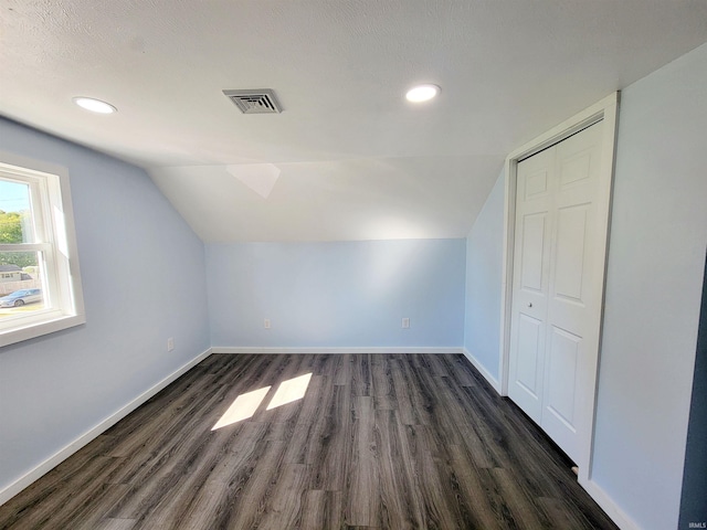 additional living space with a textured ceiling, lofted ceiling, and dark hardwood / wood-style floors