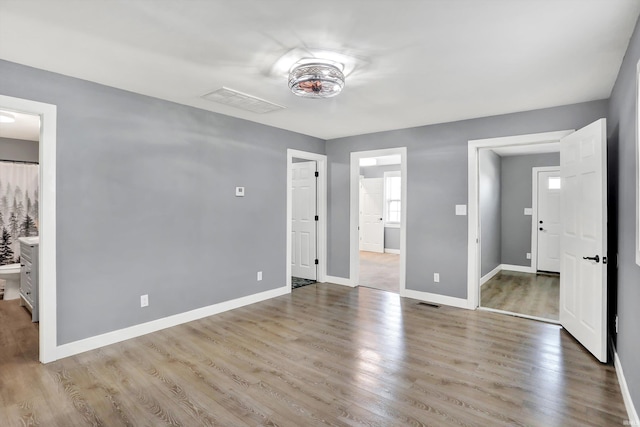 unfurnished bedroom with connected bathroom and light wood-type flooring