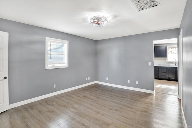 unfurnished room featuring plenty of natural light, light hardwood / wood-style floors, and sink