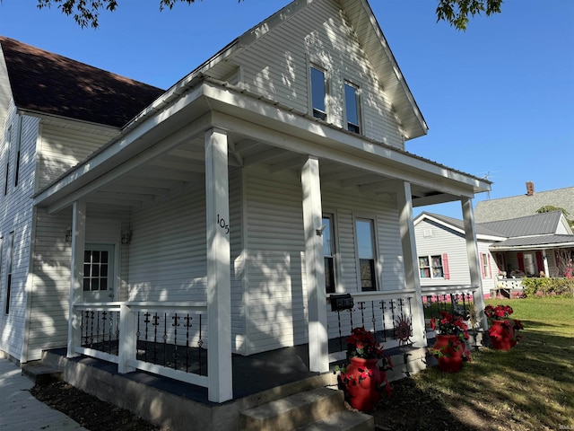 view of side of home with a lawn and covered porch