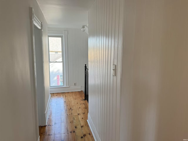 hallway with wooden walls and light hardwood / wood-style floors