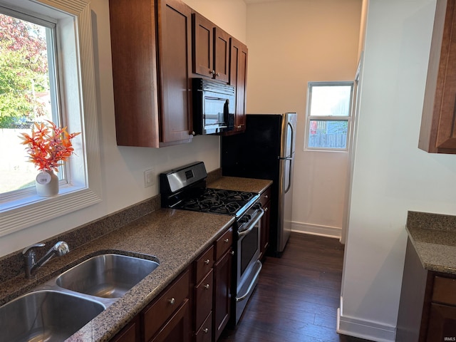 kitchen featuring stainless steel appliances, dark wood-type flooring, sink, and dark stone counters