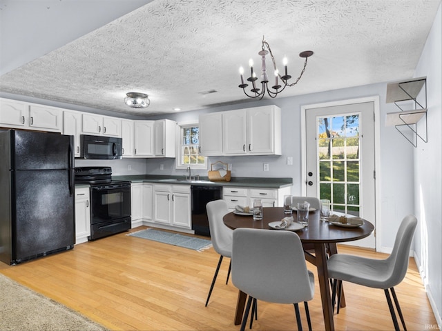 kitchen featuring light wood-type flooring, black appliances, white cabinetry, and a textured ceiling