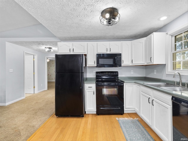 kitchen featuring sink, light wood-type flooring, white cabinetry, and black appliances