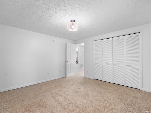 unfurnished bedroom with a closet, light colored carpet, and a textured ceiling