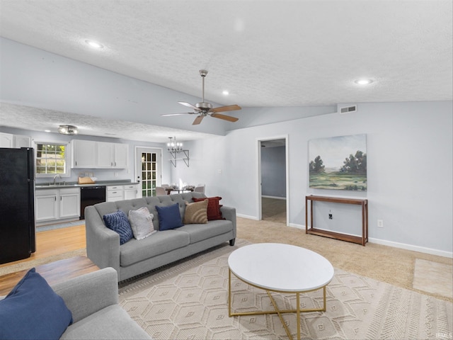 living room featuring ceiling fan with notable chandelier, a textured ceiling, lofted ceiling, and sink