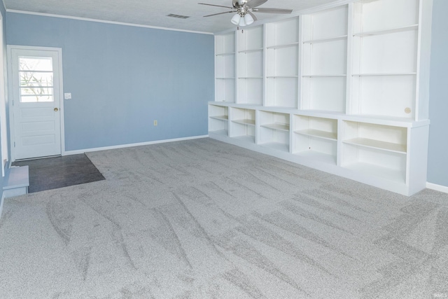 unfurnished living room featuring carpet floors, a textured ceiling, ornamental molding, and ceiling fan