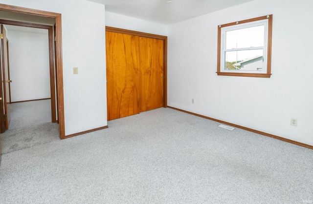 unfurnished bedroom with a closet and light colored carpet