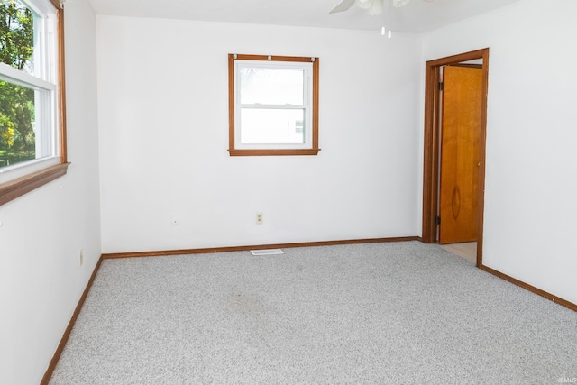 empty room featuring a healthy amount of sunlight, ceiling fan, and carpet