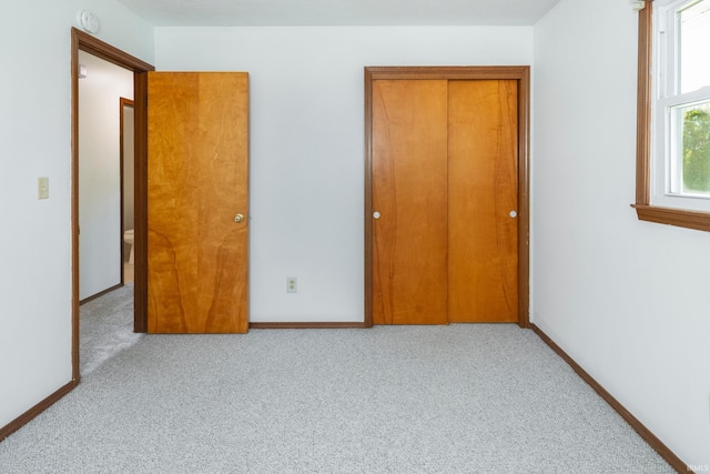 unfurnished bedroom featuring light colored carpet and a closet