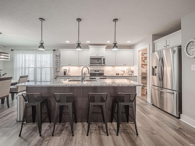 kitchen featuring hanging light fixtures, white cabinetry, and stainless steel appliances