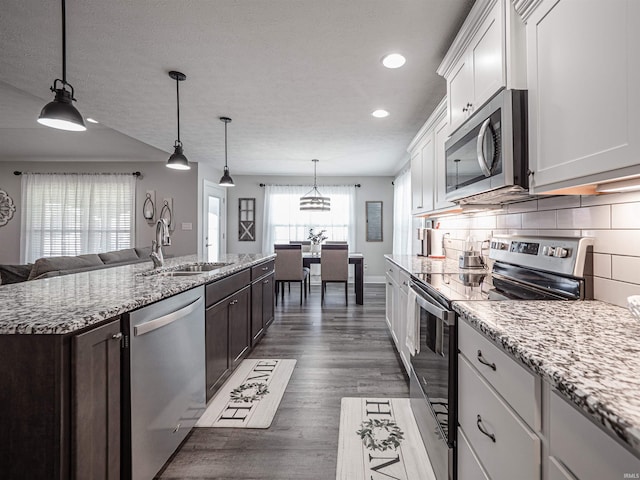 kitchen with dark hardwood / wood-style flooring, sink, hanging light fixtures, appliances with stainless steel finishes, and white cabinetry