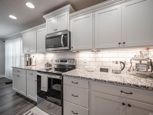 kitchen with dark hardwood / wood-style flooring, stainless steel appliances, light stone countertops, backsplash, and white cabinetry