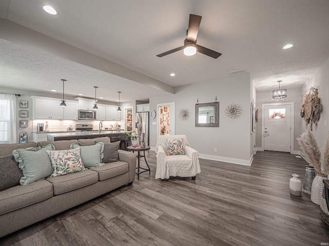 living room with ceiling fan with notable chandelier, dark hardwood / wood-style floors, and sink