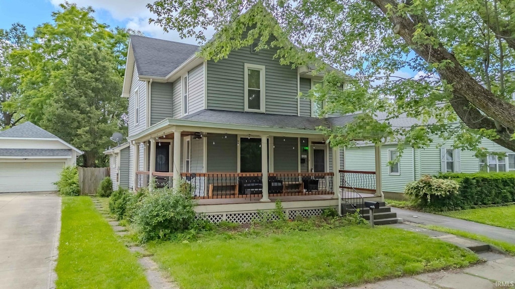 view of front of home featuring a garage, a front lawn, an outdoor structure, and a porch