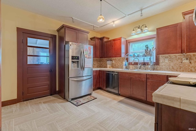 kitchen with pendant lighting, stainless steel appliances, track lighting, and decorative backsplash