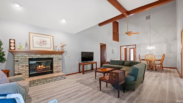 living room with a brick fireplace, high vaulted ceiling, ceiling fan, and light hardwood / wood-style floors