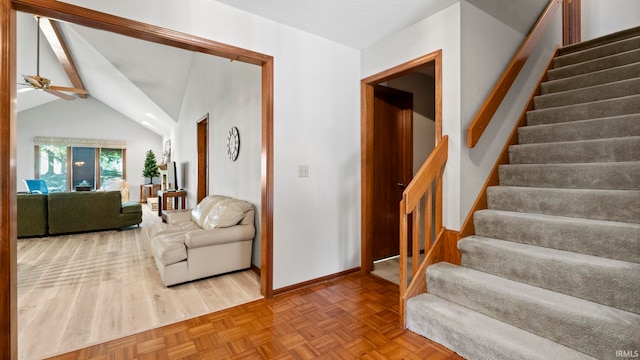 living area featuring ceiling fan, baseboards, vaulted ceiling with beams, and stairway