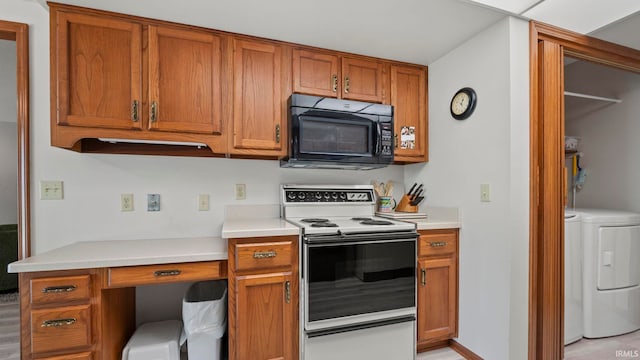 kitchen featuring black microwave, electric range, washing machine and clothes dryer, light countertops, and brown cabinets