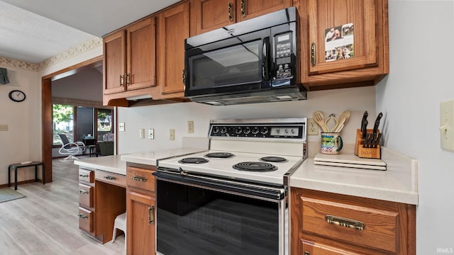 kitchen with electric stove, a textured ceiling, and light hardwood / wood-style floors