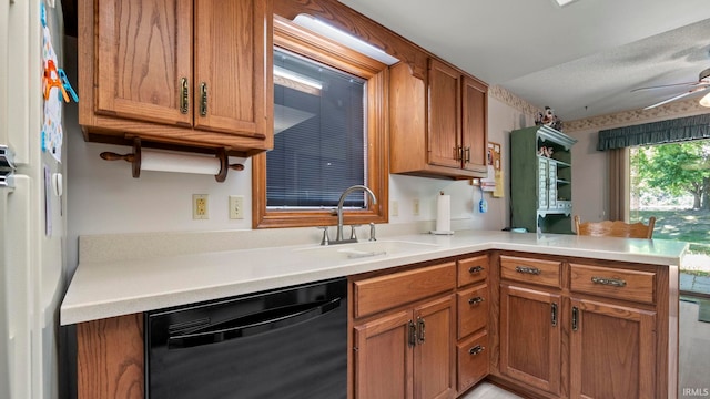 kitchen with brown cabinetry, a peninsula, dishwasher, and a sink
