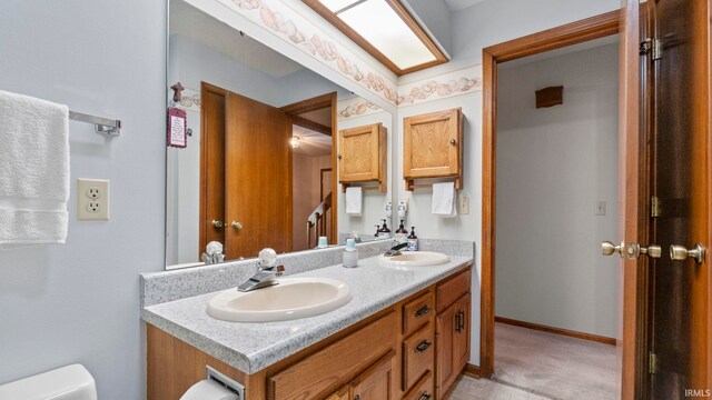 full bathroom featuring a sink, toilet, double vanity, and baseboards