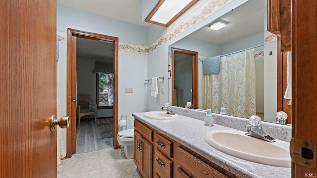 bathroom with tile patterned floors, double vanity, a sink, and toilet
