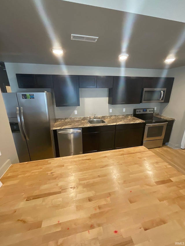 kitchen featuring light hardwood / wood-style floors, sink, stainless steel appliances, and light stone countertops