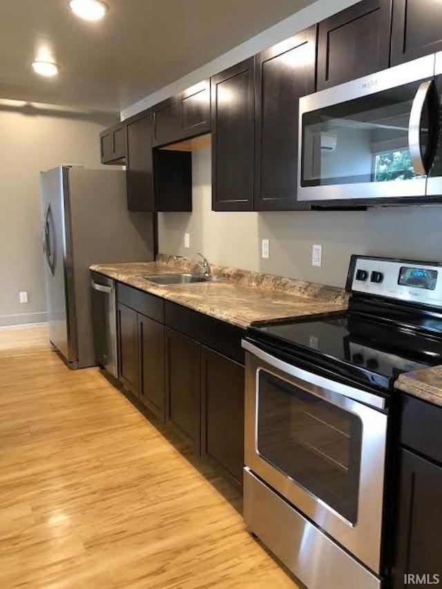 kitchen featuring appliances with stainless steel finishes, sink, light wood-type flooring, and dark brown cabinets