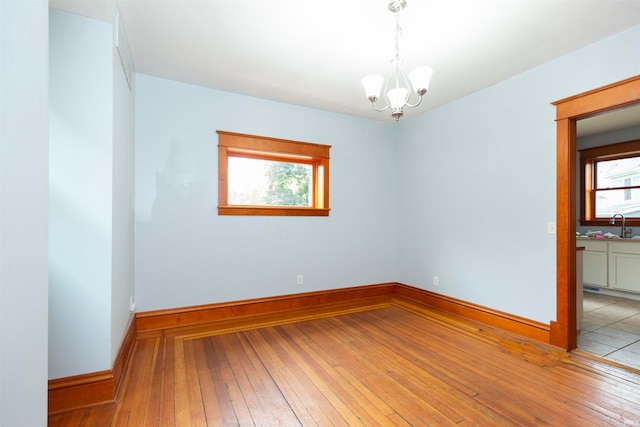 unfurnished room featuring light wood-type flooring, sink, and a chandelier