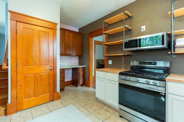 kitchen featuring appliances with stainless steel finishes, butcher block countertops, white cabinetry, and light tile patterned floors