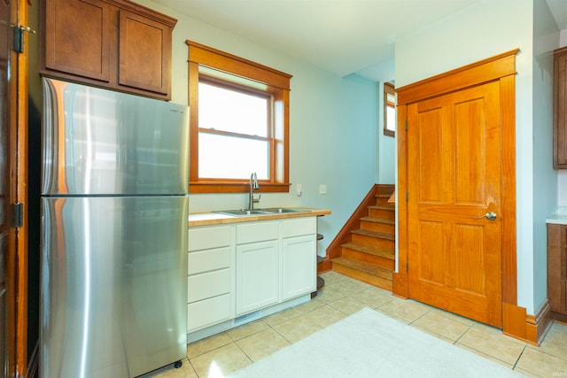 kitchen with light tile patterned floors, stainless steel refrigerator, and sink