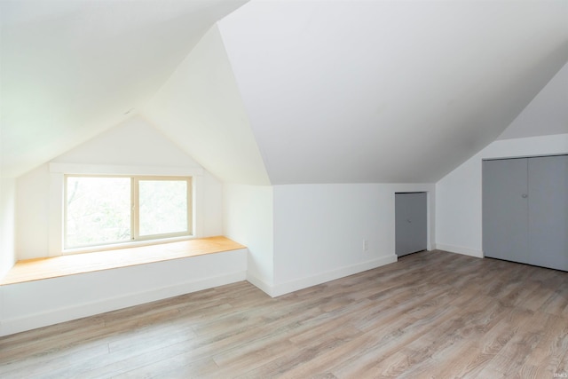 bonus room with lofted ceiling and light wood-type flooring