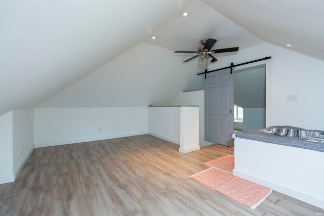 bonus room featuring lofted ceiling, a barn door, hardwood / wood-style floors, and ceiling fan