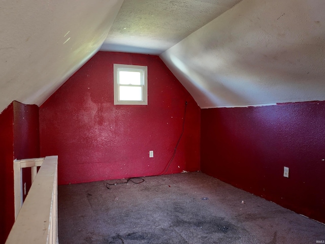 additional living space with vaulted ceiling, carpet, and a textured ceiling