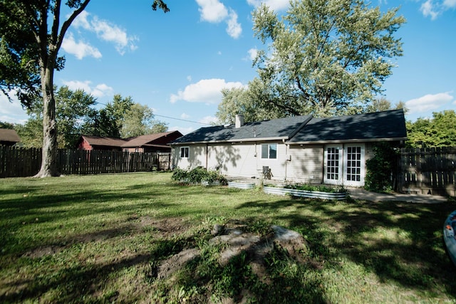 back of property with french doors and a lawn