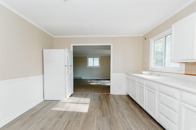 kitchen with baseboard heating, crown molding, white refrigerator, light hardwood / wood-style floors, and white cabinetry